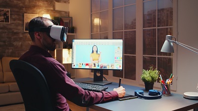 Freelancer photographer using virtual reality headset while retouching photos with graphic tablet in home office during night time.